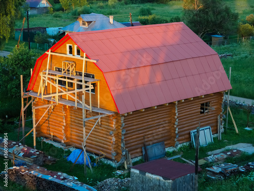 under construction a two story wooden large log house with a red roof