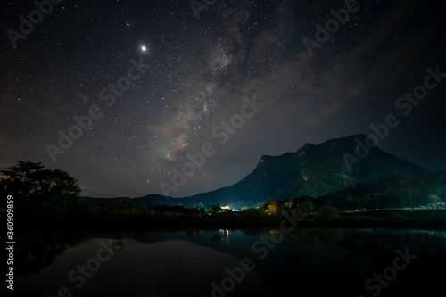 Landscape with colourful bright milky way and mountain with reflection on water. Night sky with stars..