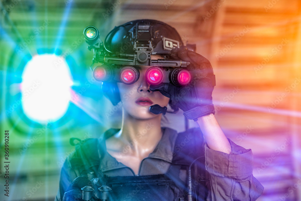 Portrait of female modern army special forces soldier, anti terrorist squad fighter, elite commando warrior using four-eyed night vision goggles in dark background Portrait of female modern army special forces soldier, anti terrorist squad fighter, elite commando warrior using four-eyed night vision goggles in dark background