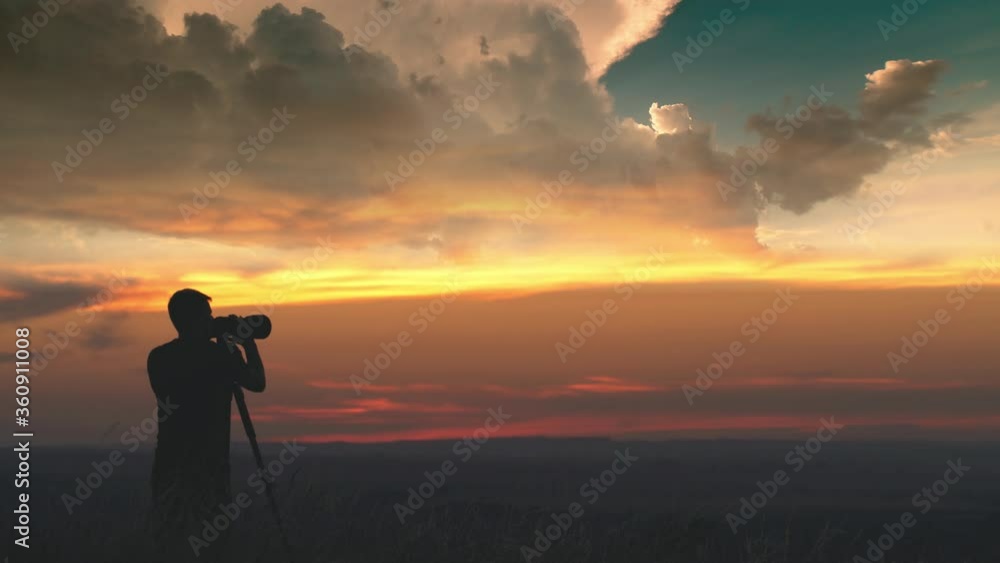 The man use the camera with tripod against the beautiful sky background The man use the camera with tripod against the beautiful sky background