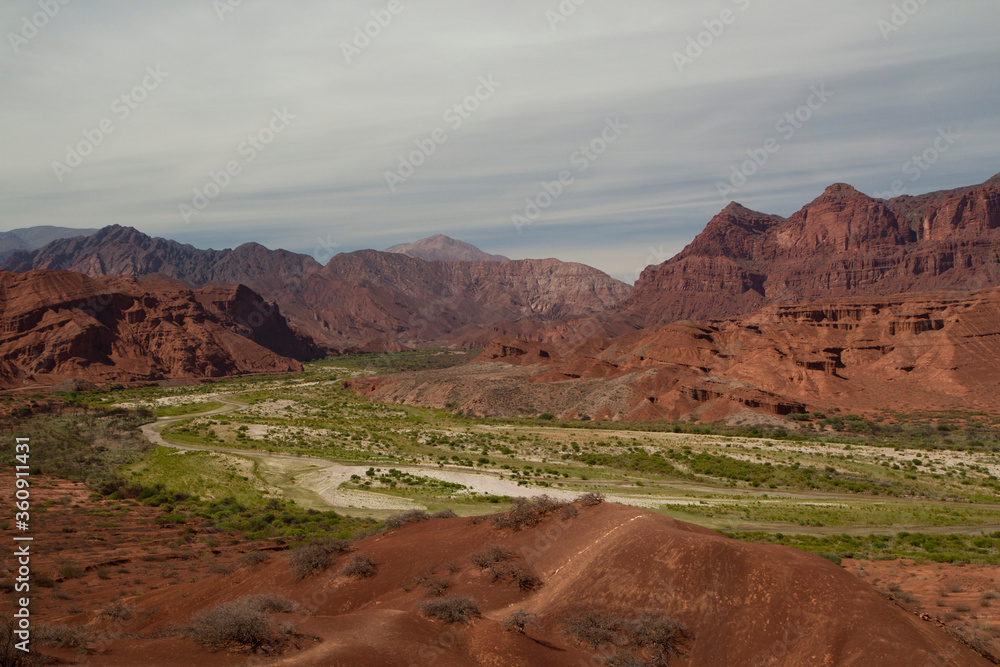 Panorama view of the valley and desert with red mountains and rocky formations.