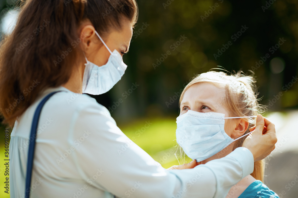 mother and child outdoors in city park wearing medical mask mother and child outdoors in city park wearing medical mask