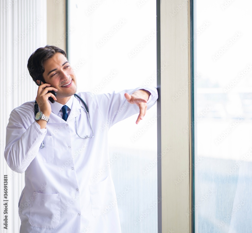 Fototapeta premium Young handsome doctor standing at the window