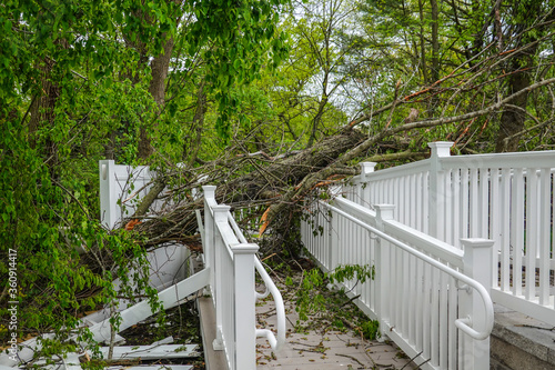 Damage to a white metal fence and guard rail of a deck and ramp from a tree that fell during a storm