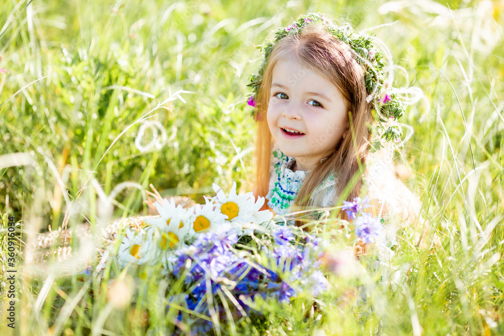 portrait of a cute little girl with a wreath on her head smiling holding wildflowers of cornflower portrait of a cute little girl with a wreath on her head smiling holding wildflowers of cornflower