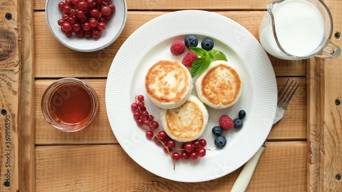 Wallpaper Mural Cottage cheese fritters or pancakes with berries and honey for breakfast on a rustic wooden table, top view. Male hand decorate syrniki with mint leaf Torontodigital.ca