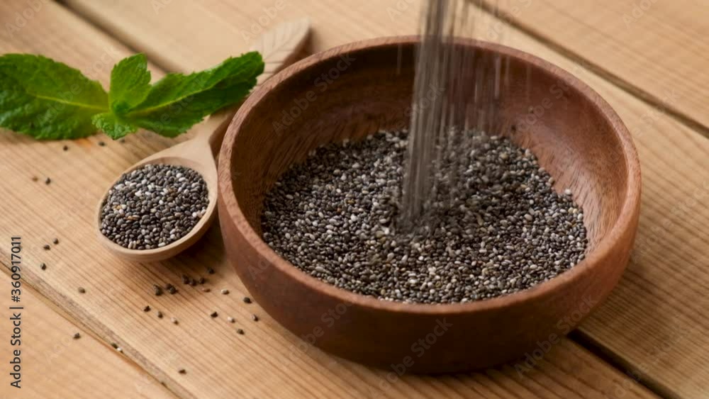 Chia seeds falling in wooden bowl in slow motion. Healthy vegan superfood Chia seeds falling in wooden bowl in slow motion. Healthy vegan superfood