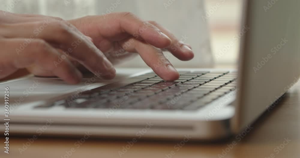 Hands of a man typing text on a beech laptop keyboard. Person sitting at the wooden desk Working He, types, writes emails, Surfs the Internet, Designs Software Hands of a man typing text on a beech laptop keyboard. Person sitting at the wooden desk Working He, types, writes emails, Surfs the Internet, Designs Software