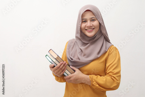 Portrait of young muslim business woman wearing hijab holding book and smiling, educational or leisure activity concept