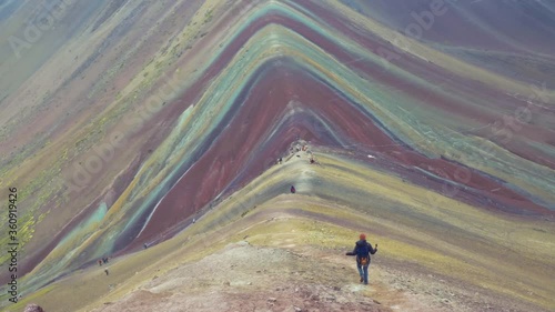 Woman walking down from the top of Vinicunca mountain, panoramic view of the Rainbow mountain in Peru. Slow motion 