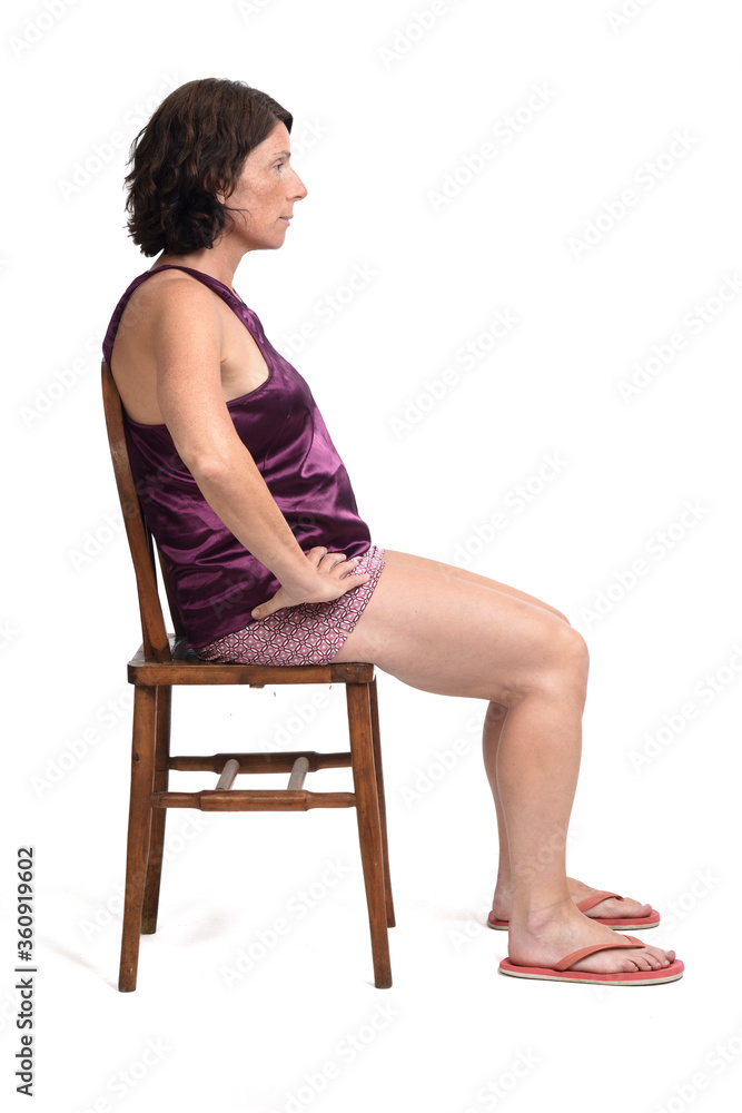 woman sitting on a chair dressed in a short summer pajamas on white background, hands on hip woman sitting on a chair dressed in a short summer pajamas on white background, hands on hip