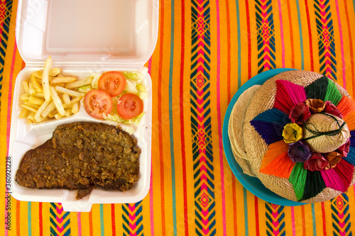 milanesa de res empanizada con ensalada y papas fritas en una plato desechable para llevar en una restaurante mexicano