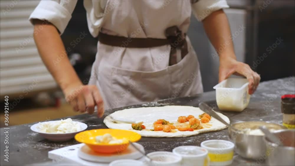 Pizza in the oven. A fire is burning in the oven. Checks pizza for readiness by pulling it out of the pizza oven using the pizza rind. Pizza in the oven. A fire is burning in the oven. Checks pizza for readiness by pulling it out of the pizza oven using the pizza rind.
