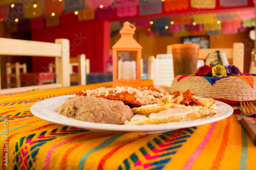 RED CHILAQUILES WITH STARRY EGGS AND REFRITTED BEANS IN A MEXICAN RESTAURANT