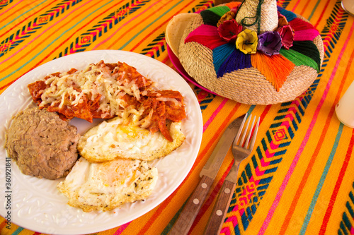 RED CHILAQUILES WITH STARRY EGGS AND REFRITTED BEANS IN A MEXICAN RESTAURANT