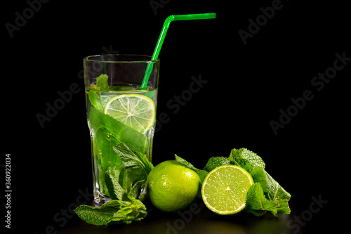 Mojito cocktail drink with fresh mint and lime on a dark background.
