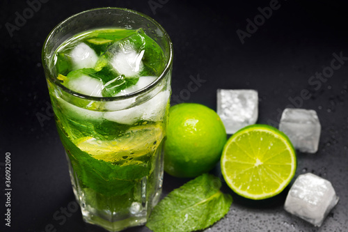 Mojito cocktail with ice, fresh mint and lime on a dark background, close-up. A refreshing summer drink.