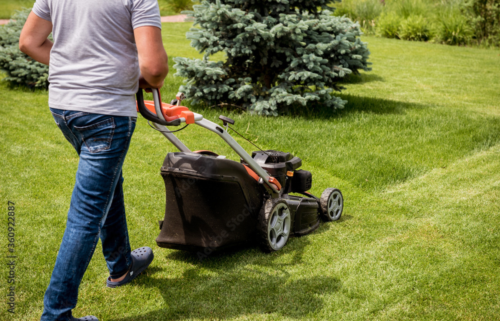 Gardener mowing the lawn. Landscape design. Green grass background Gardener mowing the lawn. Landscape design. Green grass background