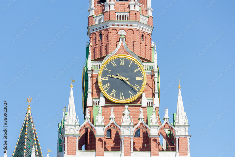 Close up view of large clock on Spasskaya Tower of Moscow Kremlin on a summer morning. Blue sky in the background. Theme of travel in Russia.
