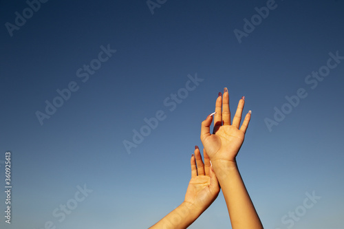 Woman hand on sky.Hands reaches for the sky.Young girl holding hands on blue sky background.Lifting hand to the sky