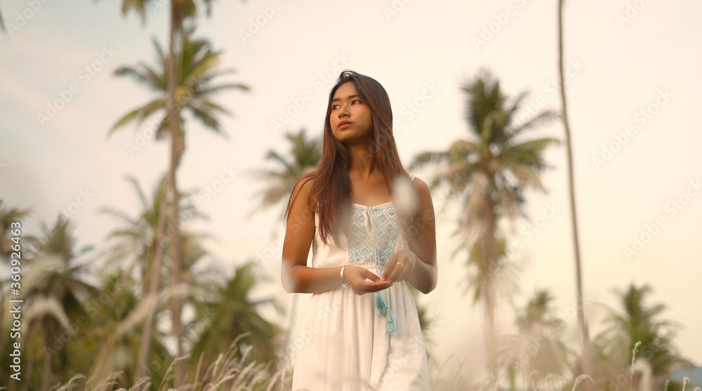 Portrait of attractive asian girl in white dress with tropical palm trees landscape Portrait of attractive asian girl in white dress with tropical palm trees landscape