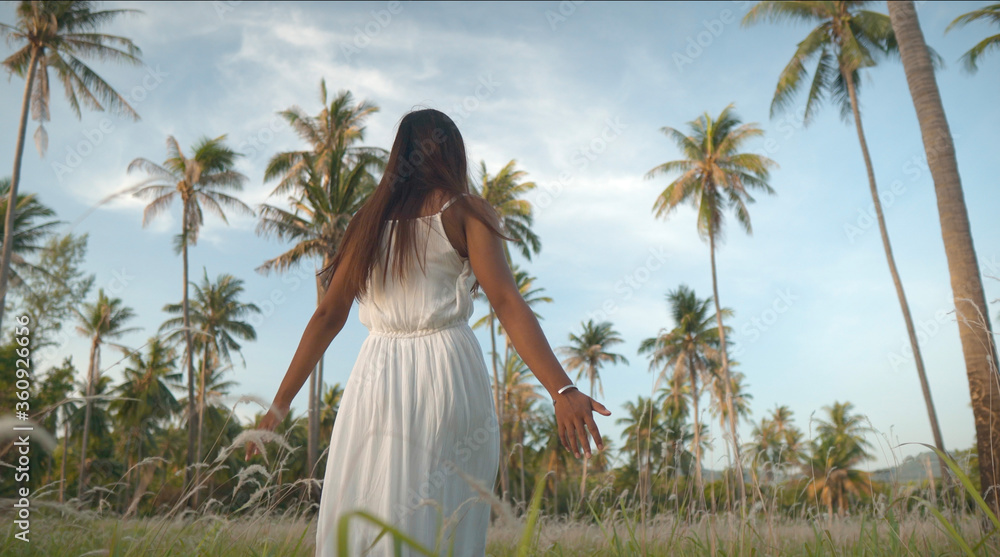 Woman on tropical island touching grass in field Woman on tropical island touching grass in field