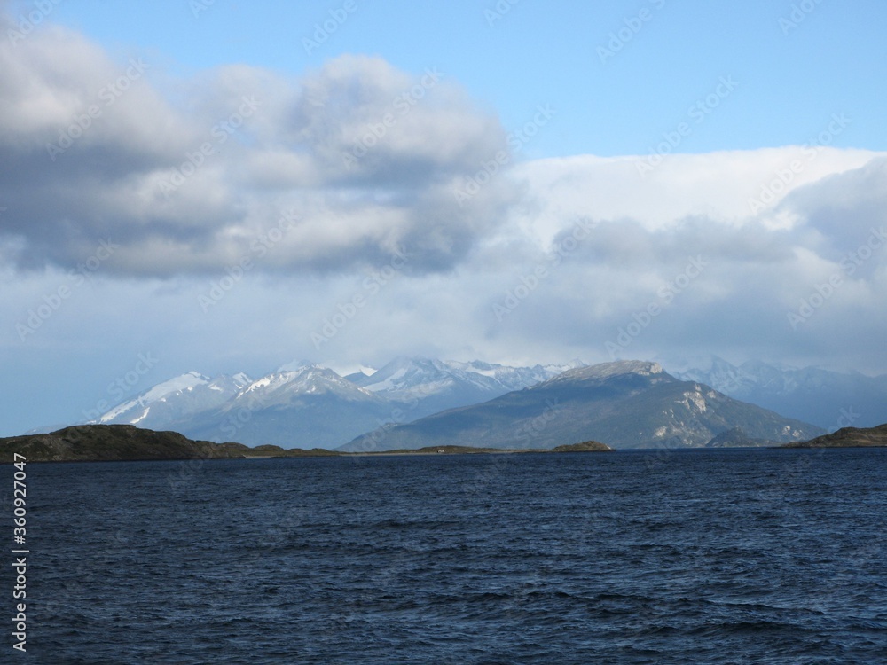 View of Tierra del Fuego (Land of Fire) and the Beagle Channel - blue water, snow-capped mountains and grey clouds, Argentina 