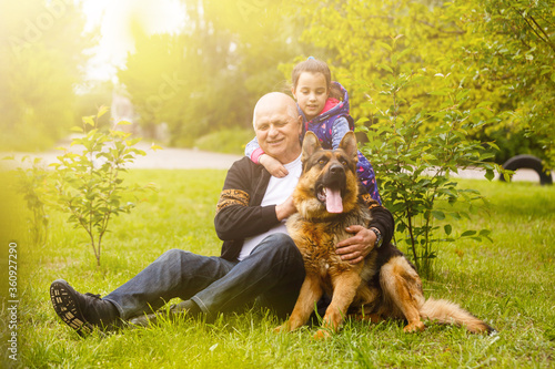 Grandfather with granddaughter and a dog in the garden