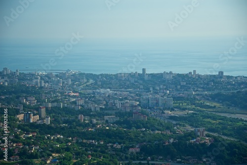 Panorama of the center of the coastal city. Lots of buildings and roads. Ships at sea. The seaport is visible. The river flows in the valley. View of the city of Sochi from above.