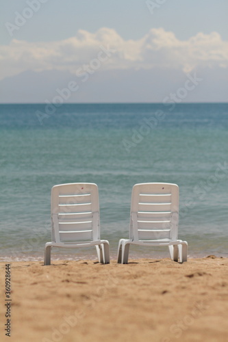Deck chair in the sand on the shore. Relax, relaxation on the beach. Blue water in the ocean sea. © Maksim Selin