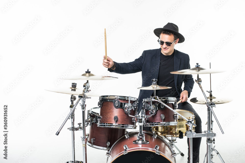 Fototapeta premium Handsome young man behind the drum kit isolated on a white background