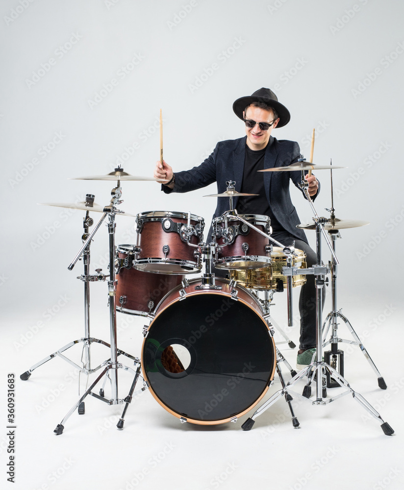 Fototapeta premium Handsome young man behind the drum kit isolated on a white background
