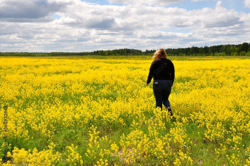 Young woman girl in black clothes in the field full of yellow flowers