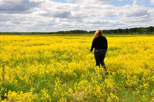 Young woman girl in black clothes in the field full of yellow flowers © Lunatishe