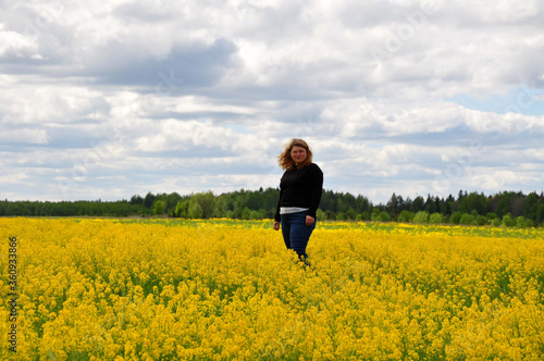 Young woman girl in black clothes in the field full of yellow flowers © Lunatishe