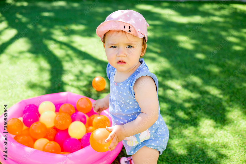 Toddler girl plays in summer with developing toys on green lawn.Toddler girl plays in dry pool Toddler girl plays in summer with developing toys on green lawn.Toddler girl plays in dry pool