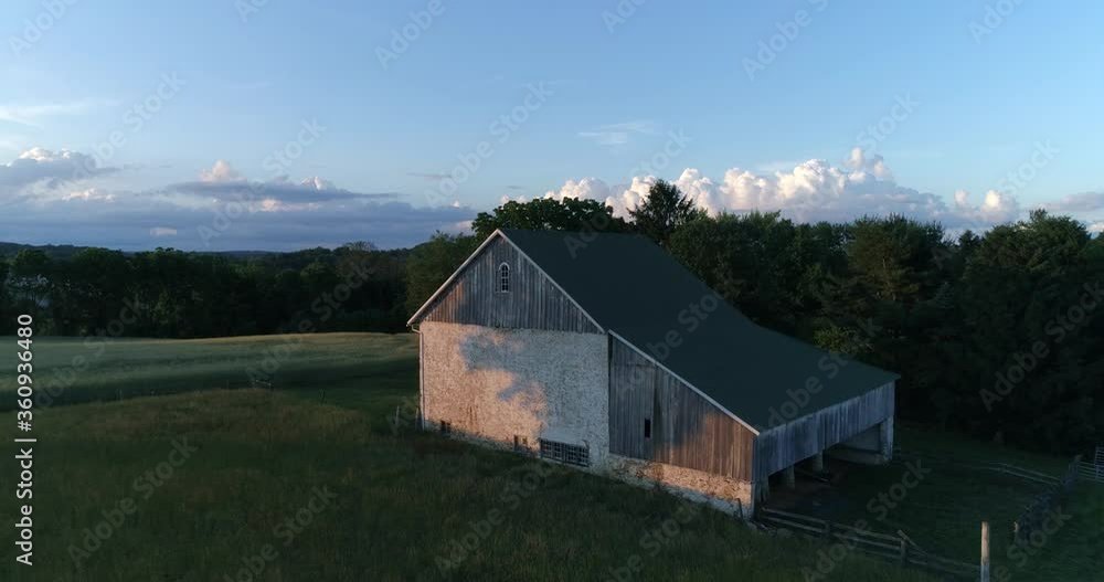 A barn surrounded by a wheat field in the rural Pennsylvania countryside during a beautiful sunset, aerial drone shot A barn surrounded by a wheat field in the rural Pennsylvania countryside during a beautiful sunset, aerial drone shot
