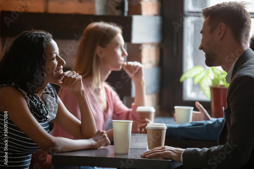 Photos Multi ethnic couples sitting in cafe enjoy chatting, focus on African girl flirting with Caucasian guy during speed dating romantic meeting participation