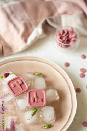 Pink chocolates lie on ice. Place for photo. 