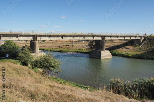 Road bridge over the river. Summer, sunny day, blue sky, calm flow of water.