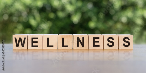 The word WELLNESS written on wooden cubes on wooden tables. Relax and care. Medical and health concept