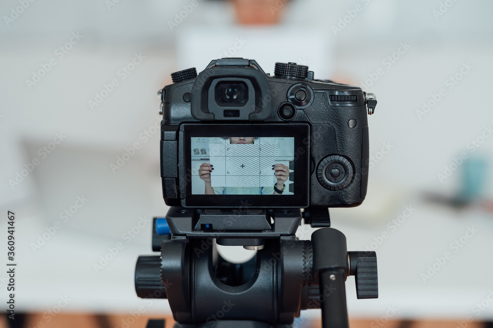 Online school. Young woman showing a blank sheet of paper at camera while recording online lesson at home. Close up photo of photo equipment. Focus on camera screen