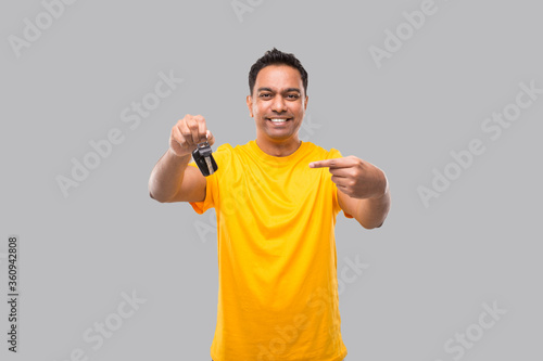 Indian Man Smilling Pointing at Car Keys Isolated. Driver