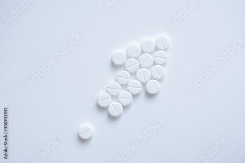 Pills laid out on a white background in the shape of an arrow shape pointing up. The concept of development, growth, increase in volume and business growth. For a pharmaceutical company. Top wiew.
