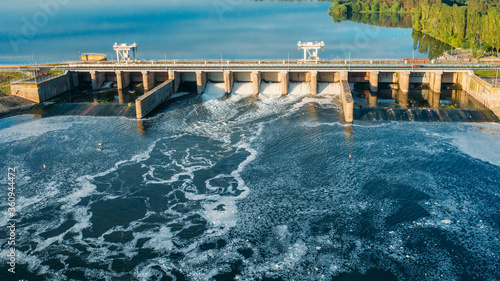 Dam with flowing water through gates. Hydroelectric power station, aerial top view.