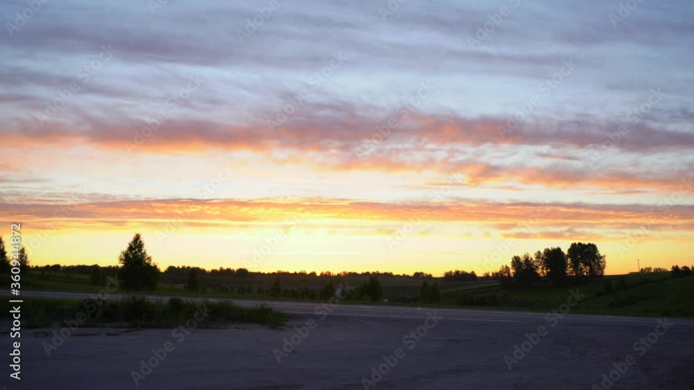 Sunset in the countryside and road with passing cars Sunset in the countryside and road with passing cars
