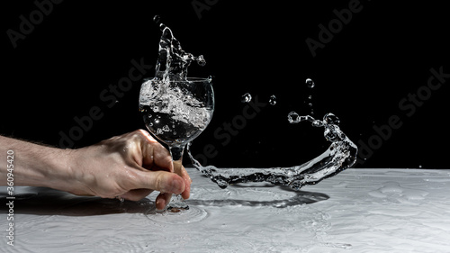 Water Splash in a Wine Glass on a Table. Water Frozen Action Shot Wallpaper. Person Spilling a Drink Isolated Background. Hand Holding a Crystal Glass Beverage