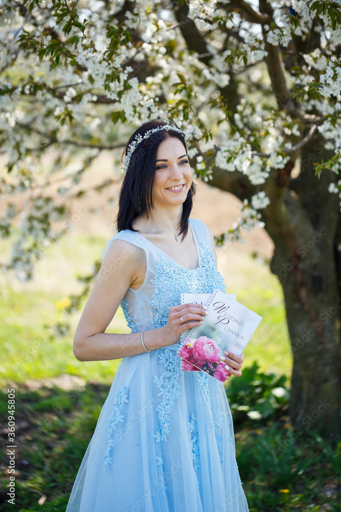 Young woman in a blue long dress holds a wedding glider in her hands