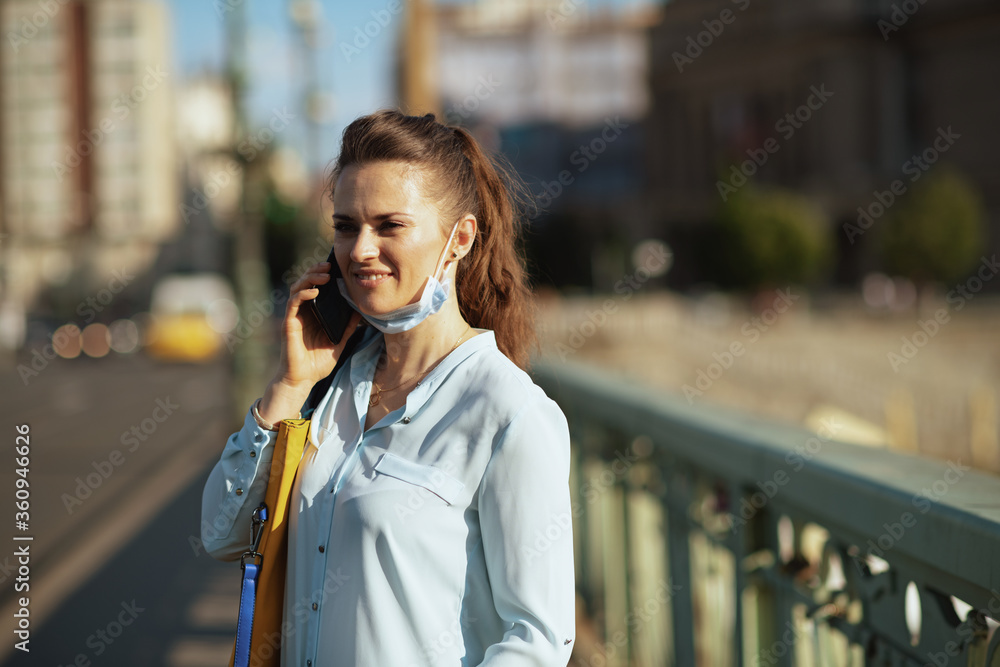 smiling trendy female using smartphone outdoors in city
