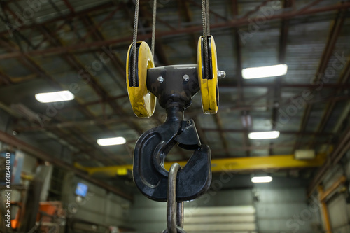 Φωτογραφία selective focus close up view of lifting hook with safety latch attached to sheaves suspended by wires ropes, factory or workshop interior background